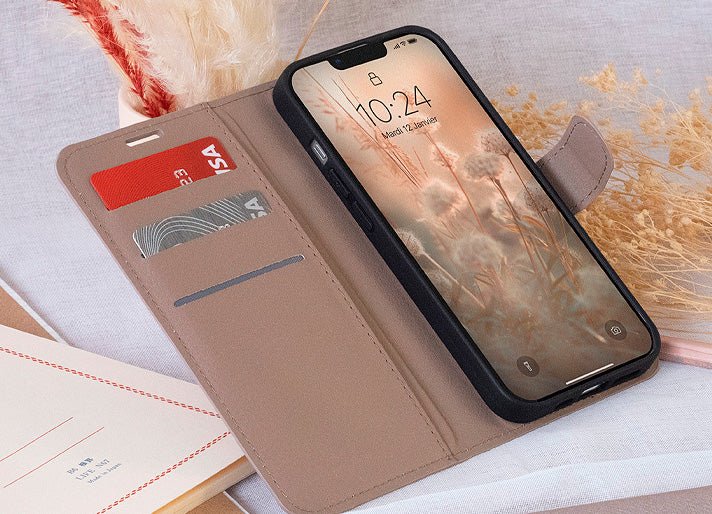 Smartphone dans un étui portefeuille beige élégant posé sur un tissu clair avec cartes insérées.
